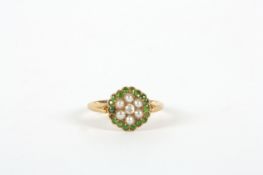 An 18ct gold circular cluster ring, set with emeralds, seed pearls and centre diamond In good