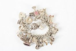 A silver curb link charm bracelet, with approximately 26 charms, weight 4.83ozt