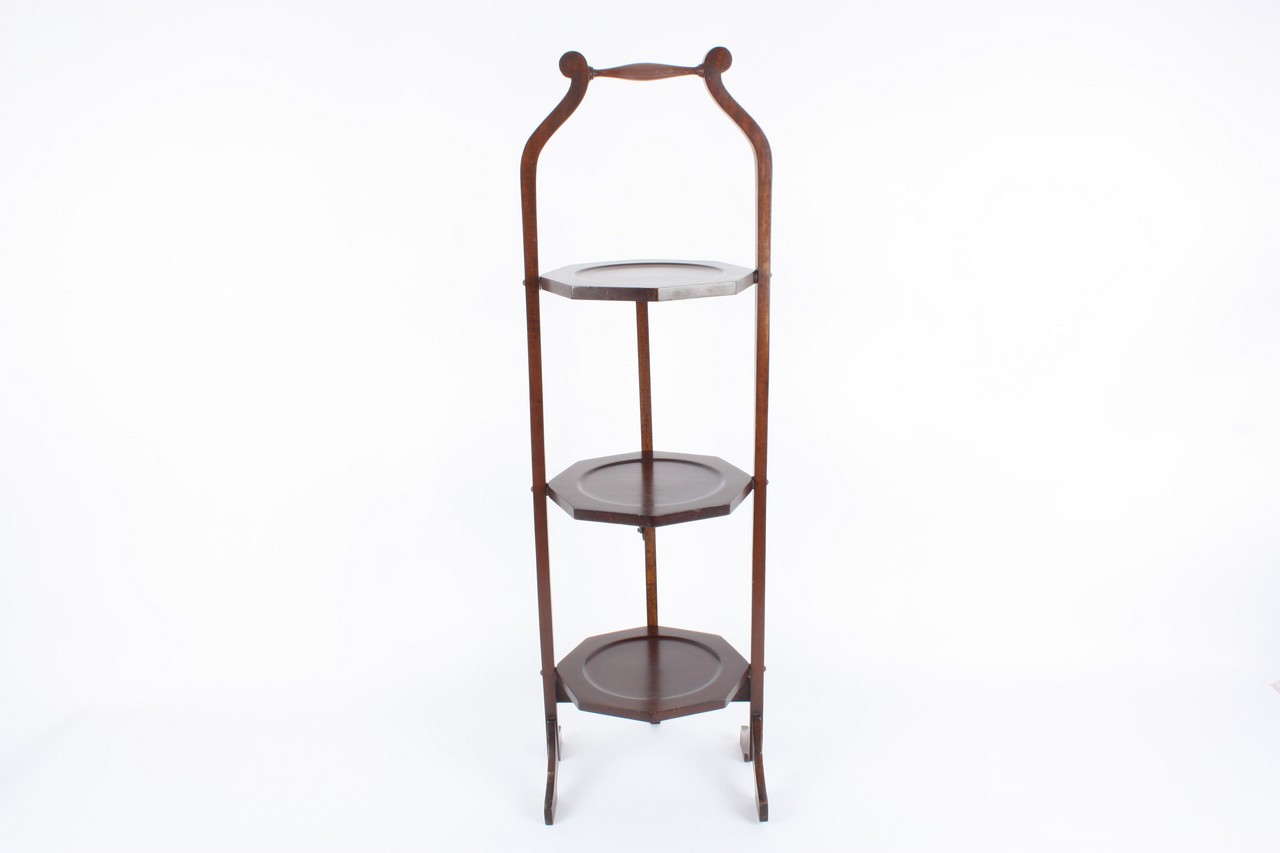 An oak double cake stand, the collapsible stand opening out to reveal two shelves each with plate