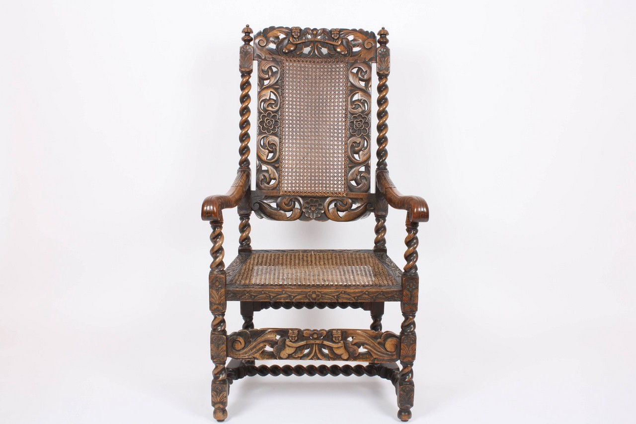 A James II style carved walnut open armchair, early 20th century, the top rail carved with a pair of