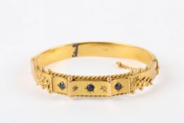 A 9ct gold 19th century stiff bangle, set with two sapphires, two rose diamonds and centre blue