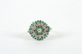 An 18ct white gold diamond and emerald cluster ring, in circular setting, claw set In good overall