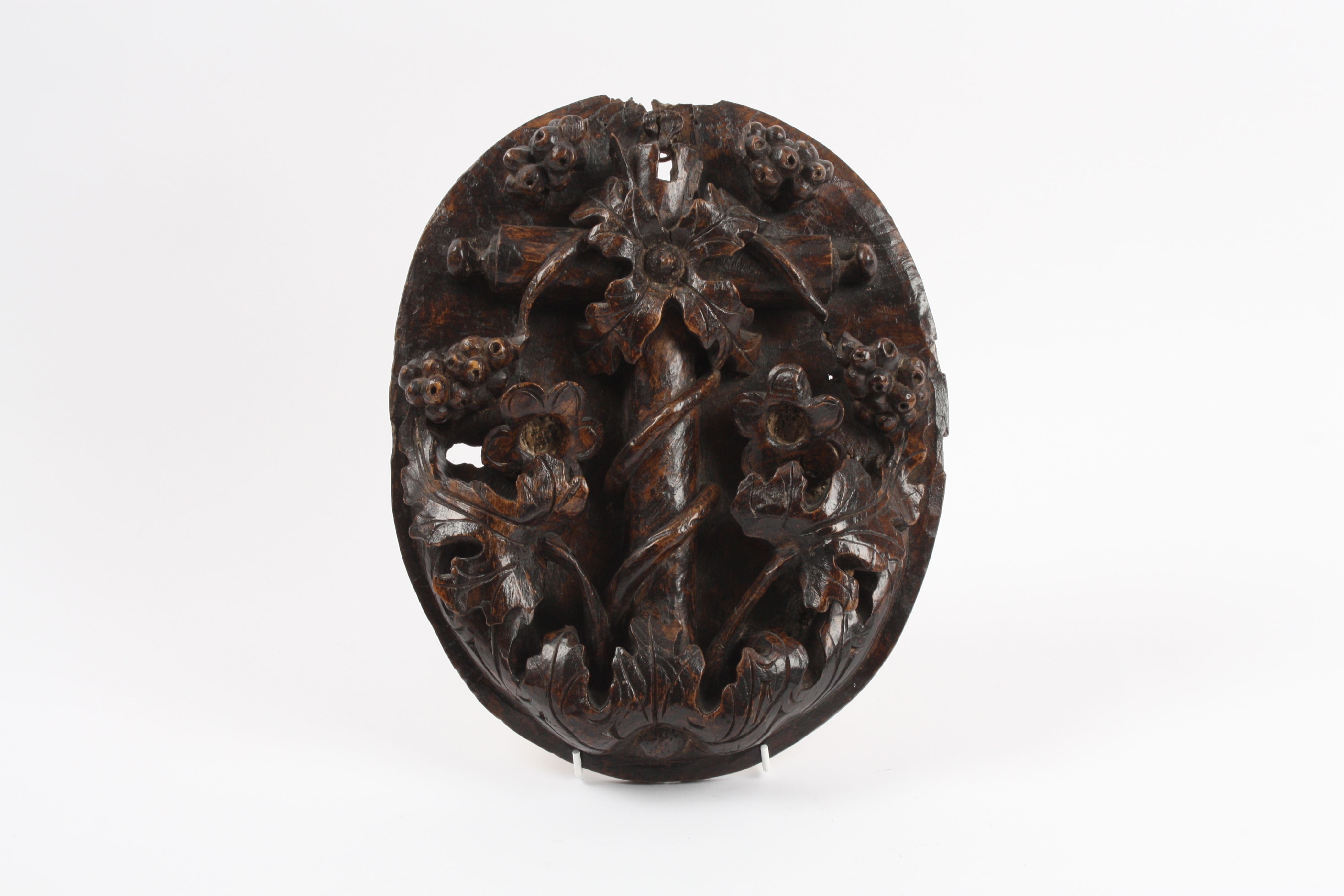 A 17th century carved oak oval lock panel ornately and deeply carved in relief with flowers,