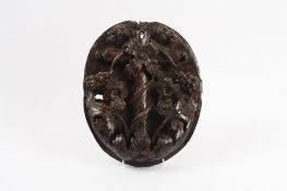 A 17th century carved oak oval lock panel ornately and deeply carved in relief with flowers,