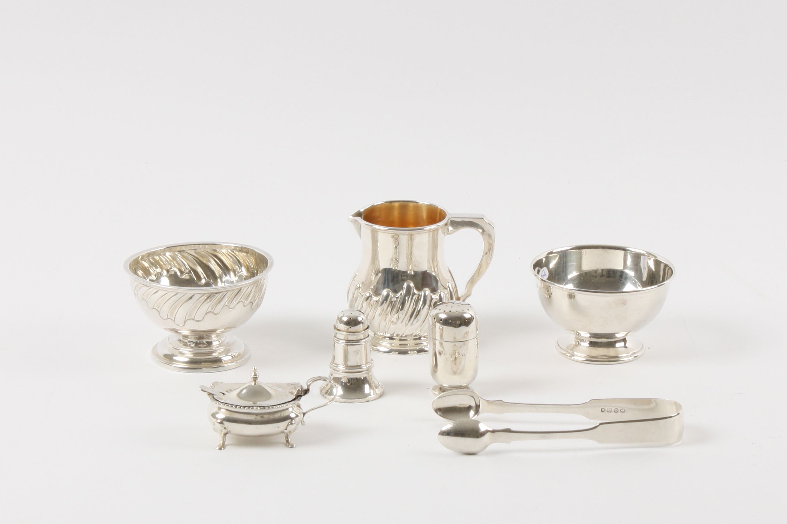 A collection of assorted silver objects comprising a wrythen fluted milk jug and sugar bowl, a plain