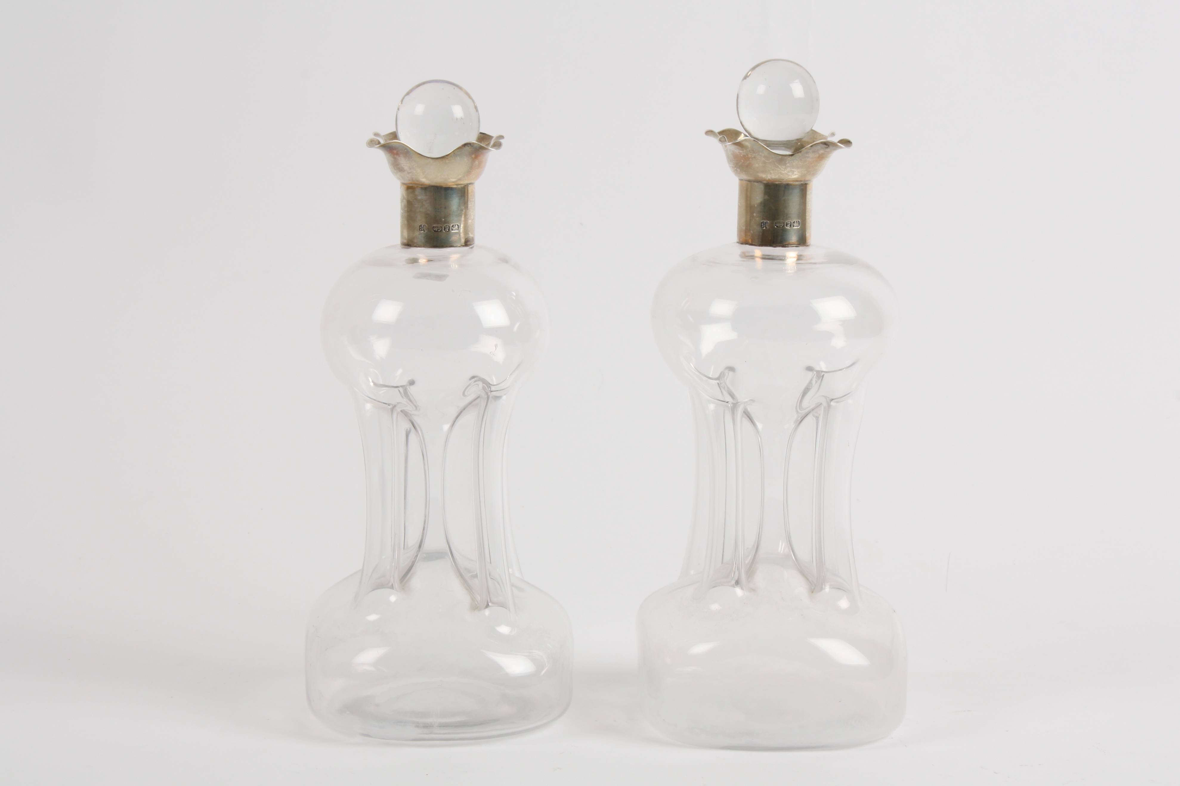 A pair of Victorian silver topped pinched glass decanters and stoppers hallmarked Birmingham 1898.