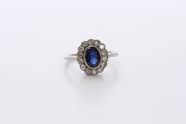 An Art Deco sapphire and diamond flower head ring set with central oval sapphire, surrounded by 14