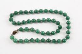 A Chinese dark green jade bead necklace of 48 10mm beads, set with an oval silver filigree clasp.