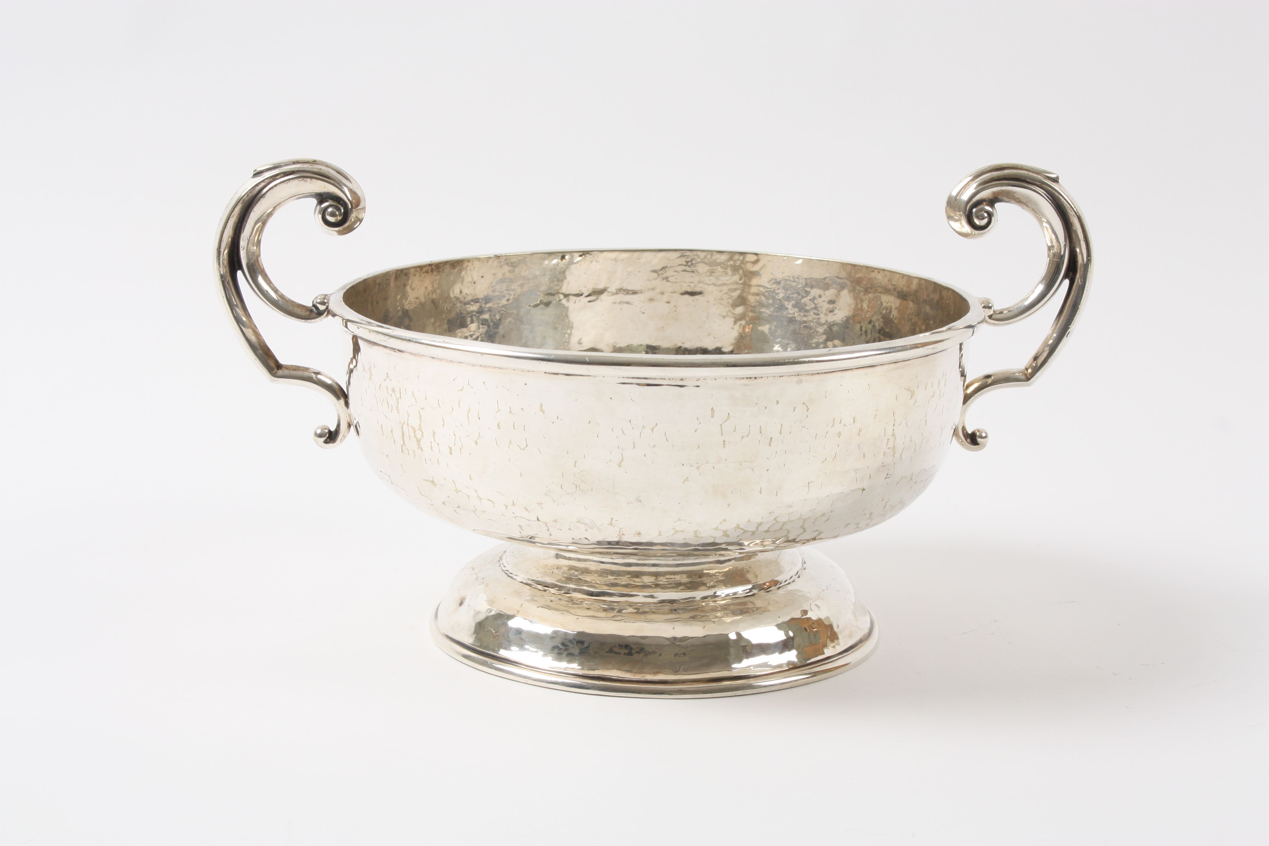 A large Arts & Crafts silver plated hand hammered circular fruit bowl of deep dished form with