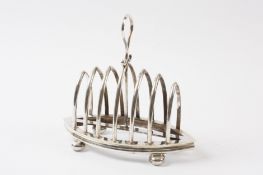 An EPNS boat shaped toast rack with six divisions, looped handle, and supported on bun feet. 18cm