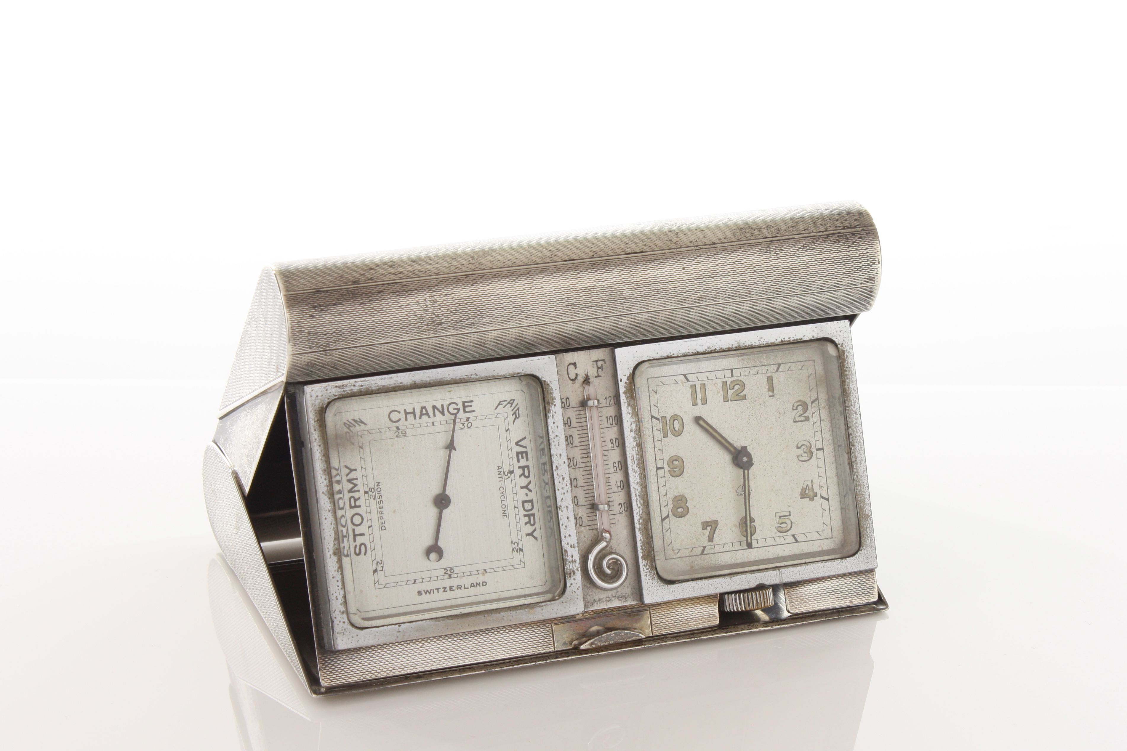 An Asprey engine turned silver travelling clock barometer hallmarked Birmingham 1938, of hinged fold