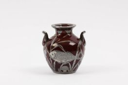 An early 20th century red porcelain and silver overlaid vase decorated with fish swimming amongst