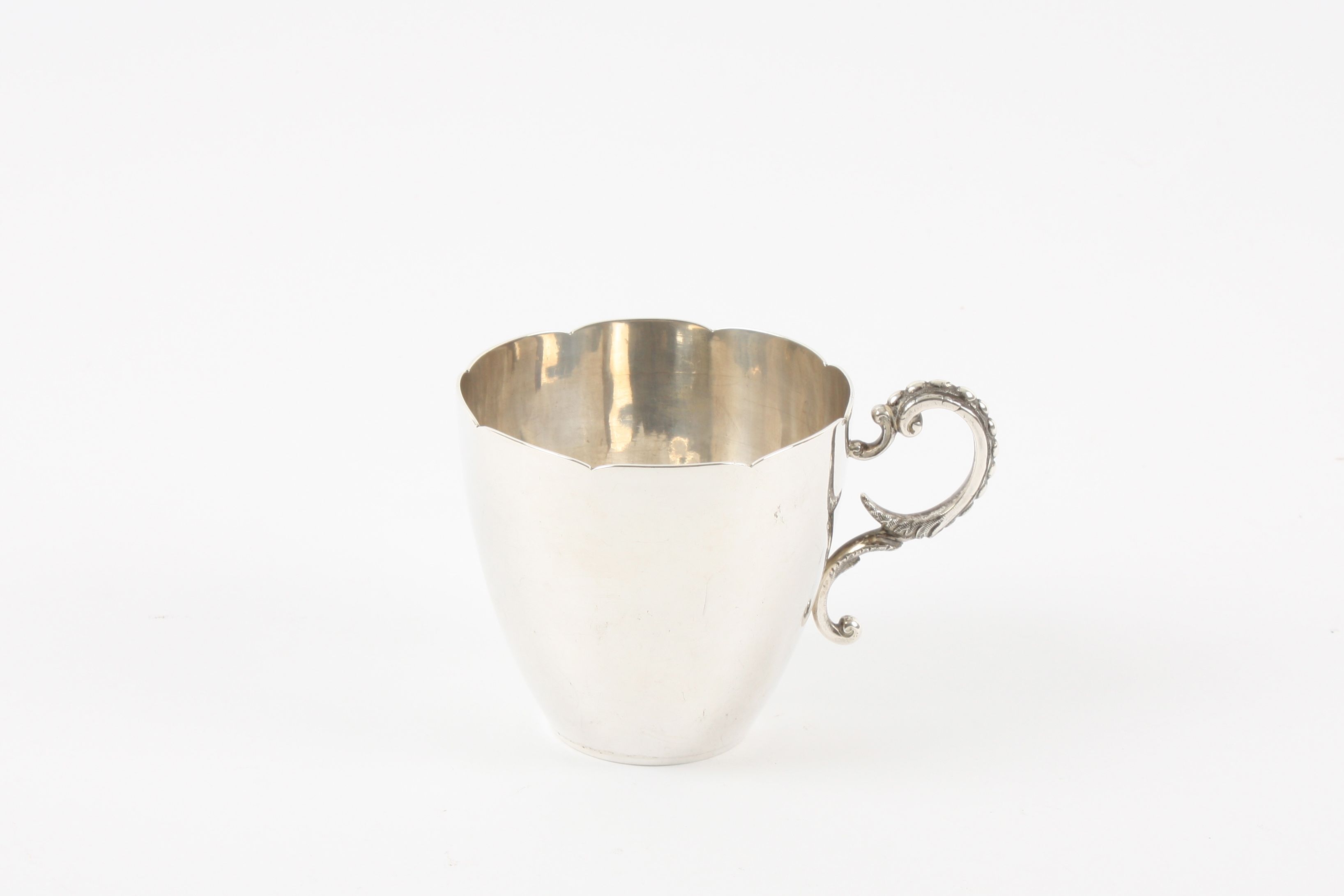 A Victorian white metal cup, with fluted rim and tapered body, with cast scrolled and beaded handle.