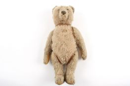 A 1930s mohair teddy bear with articulated head, arms and legs, with glass eyes. 33cm long. The