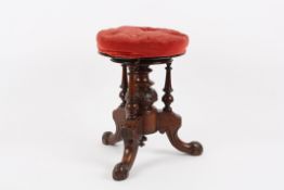 A Victorian carved mahogany piano stool?with revolving top, padded seat and supported on three