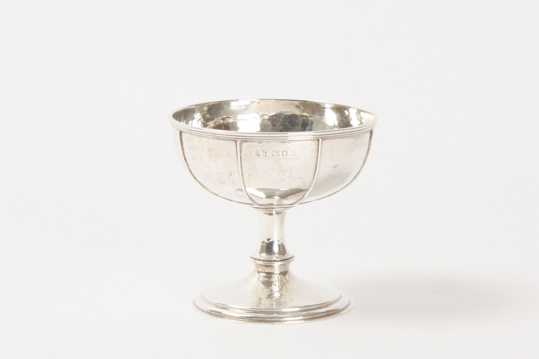 An Omar Ramsden hammered silver stem cup hallmarked London 1924, the hand hammered body with applied