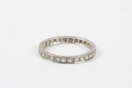 An Art Deco white gold and diamond eternity ring with scroll engraved mount. Generally good