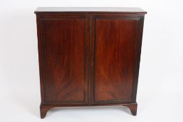 A George III mahogany shelved cupboard?with two panel doors opening to reveal a central set of