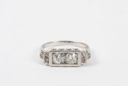 An Art Deco diamond ring set with two large diamond in a rectangular frame, with stepped diamond set