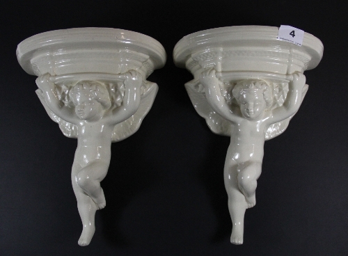 A pair of Broadstone Pottery cream ware cherub wall brackets