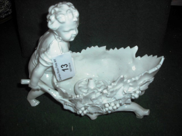A 19th century Continental white gloss glazed figure of a child with a wheelbarrow, decorated with
