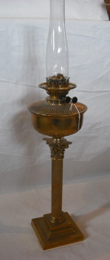 A late Victorian paraffin lamp, having clear glass chimney, reeded brass reservoir on a Corinthian