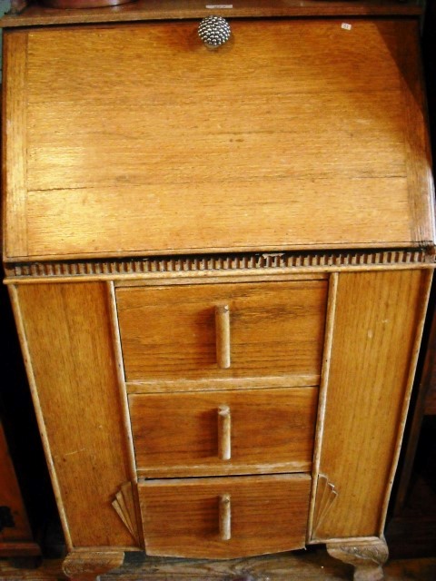 An early 20th century oak bureau, the fall with later handle enclosing a simply fitted interior over