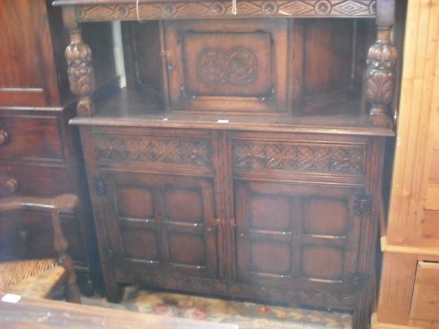 An early 20th century oak court cupboard, the rectangular moulded edge top over lozenge and flower
