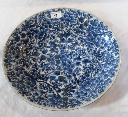 A Kanxi porcelain charger, hand decorated in underglaze blue with busy floral forms, 36cm diameter.