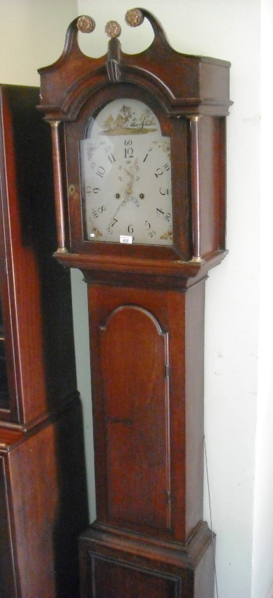 An early 19th century oak longcase clock, the hood with scrolled pediment above arched door,