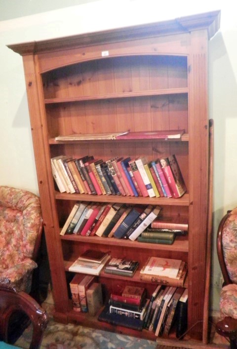 A modern pine open bookcase, having moulded cornice and arched frieze over five adjustable shelves,