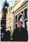 Alan Bennett signed 12x8 colour photo portrait with old buildings in background. Good condition