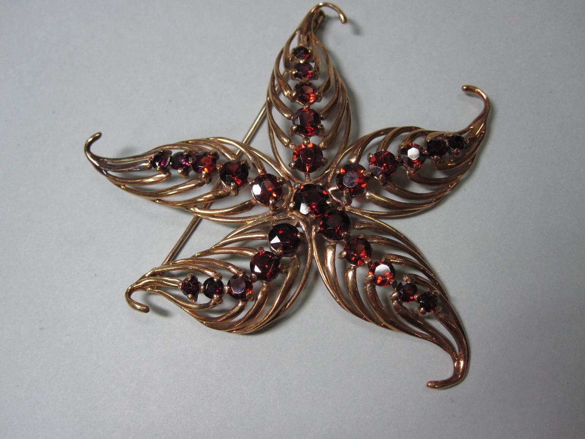 A mid 20th century garnet set flower brooch, of pierced asymmetric design with five veined boteh-