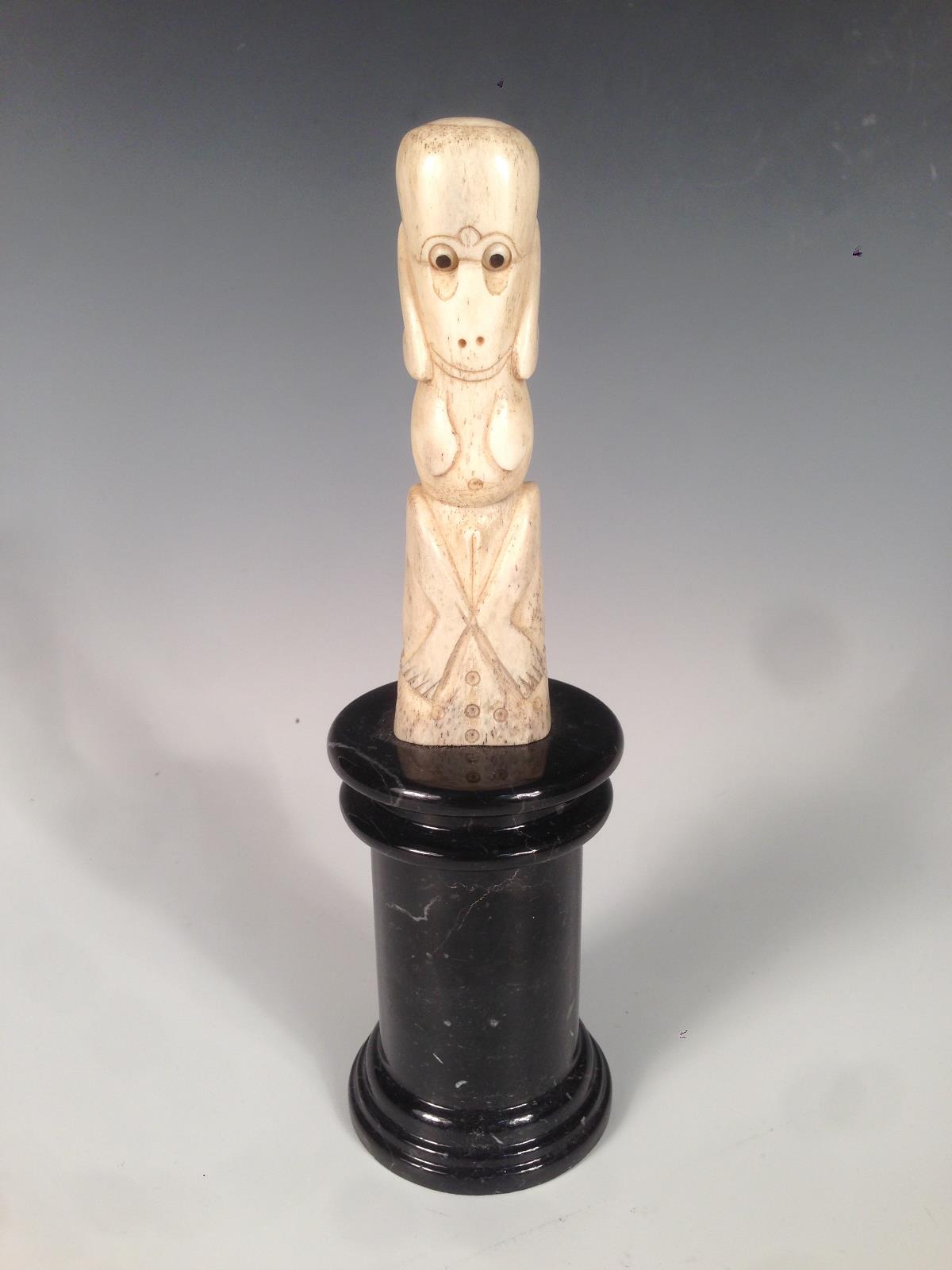 A New Zealand bone teko teko carved as a female, the naked stylised figure seated holding her hands