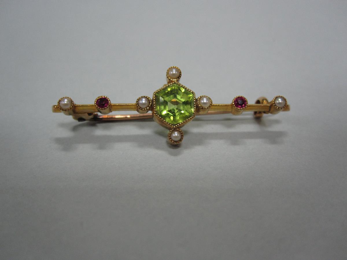 A peridot, seed pearl and ruby bar brooch in fitted case, the central hexagonal cut peridot in