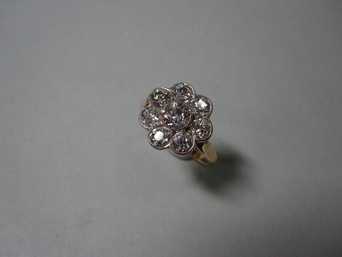 A diamond flowerhead cluster ring, composed of eight old round brilliant cut diamonds millegrain