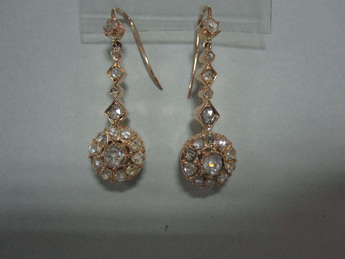 A pair of diamond pendant earrings, each hook headed by a rose cut diamond suspending a graduated