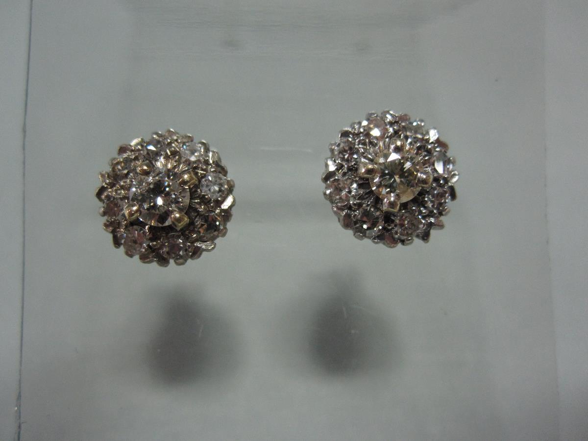 A pair of diamond cluster earstuds, each with a central round brilliant cut diamond four claw set