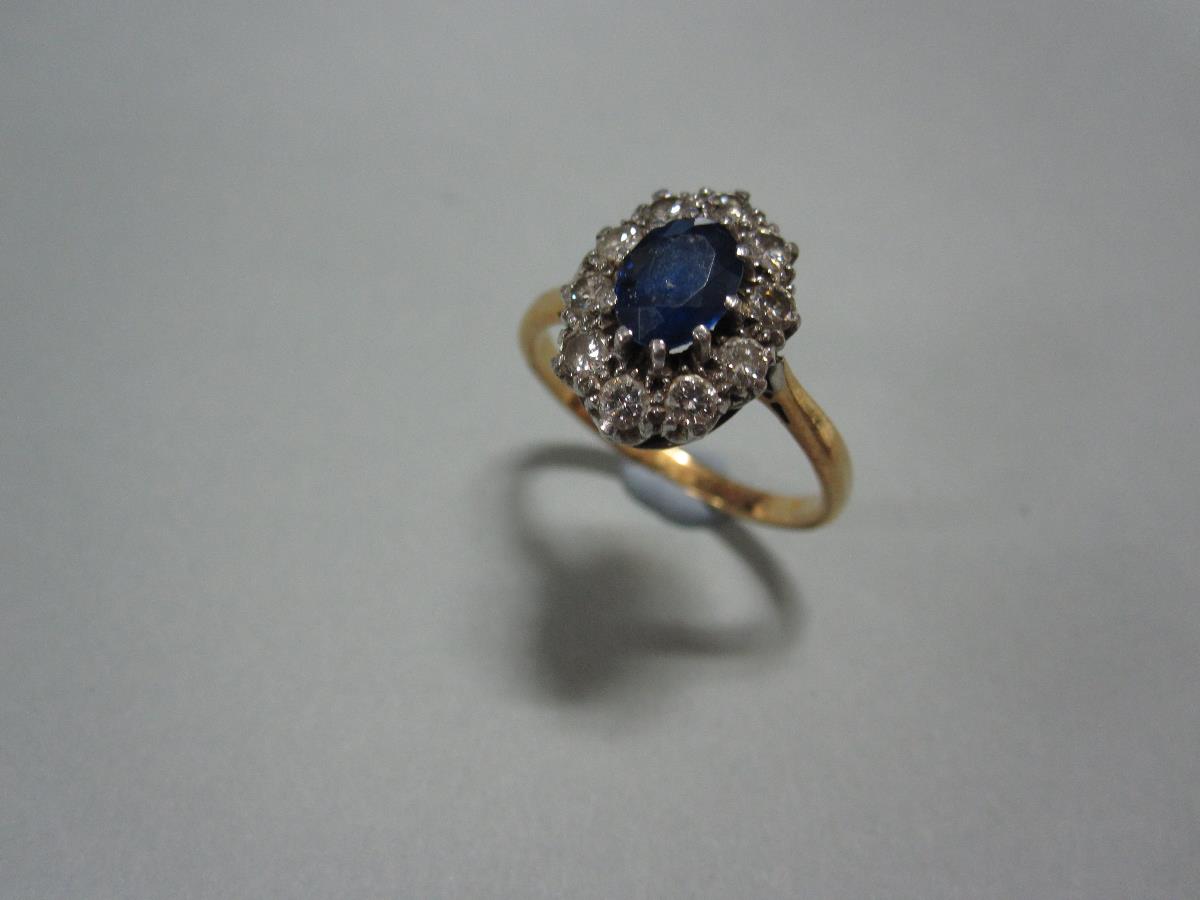 A sapphire and diamond cluster ring, the oval cut sapphire claw set in a border of ten round