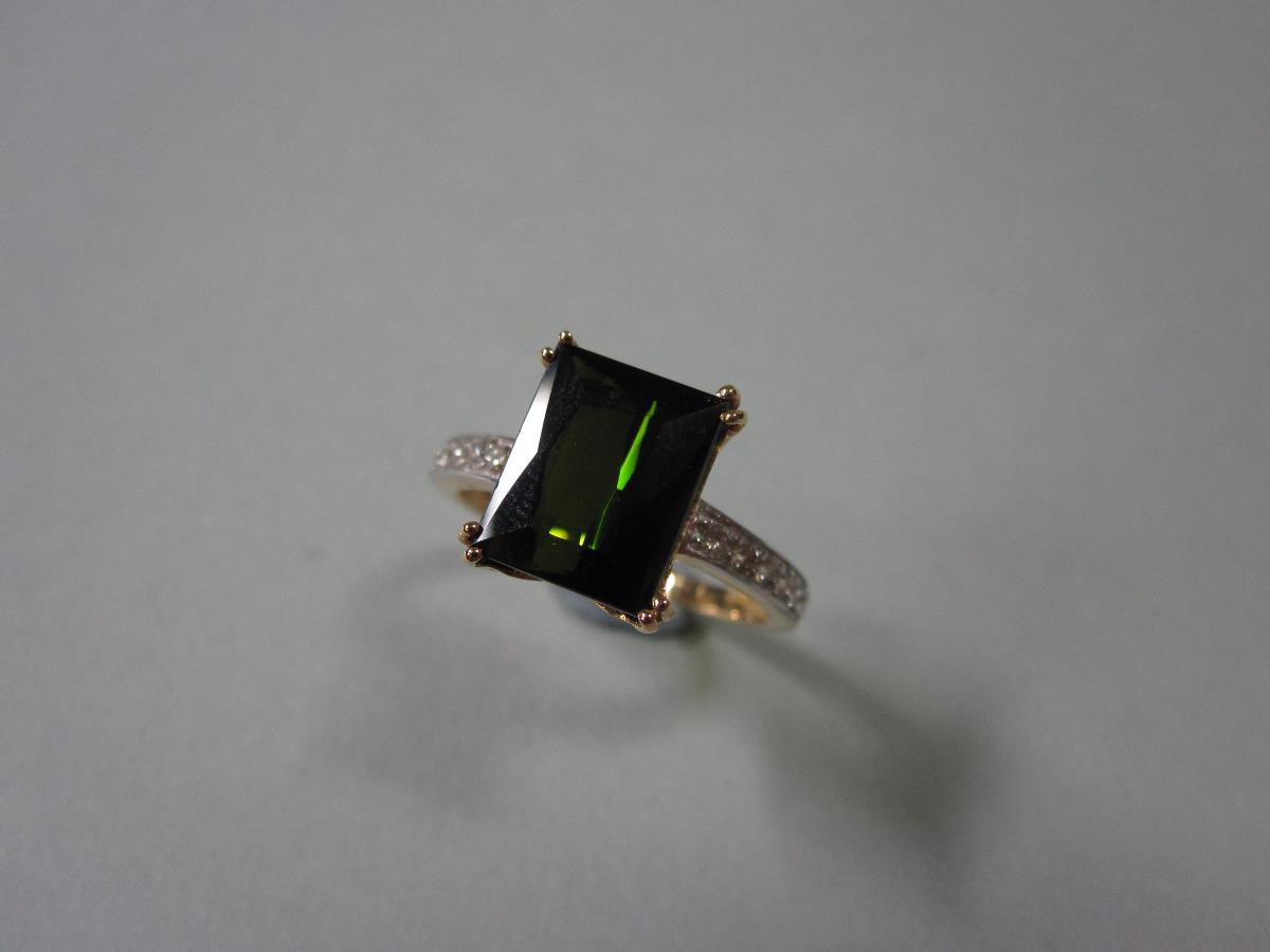 An 18ct gold green tourmaline and diamond ring, set with a scissor cut bottle green tourmaline in