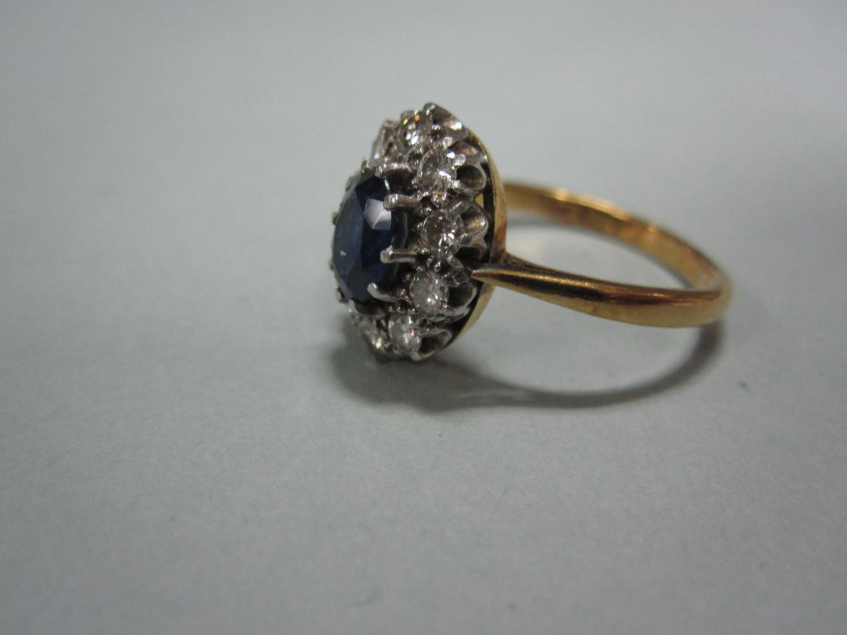 A sapphire and diamond cluster ring, the oval cut sapphire claw set in a border of ten round - Bild 2 aus 4