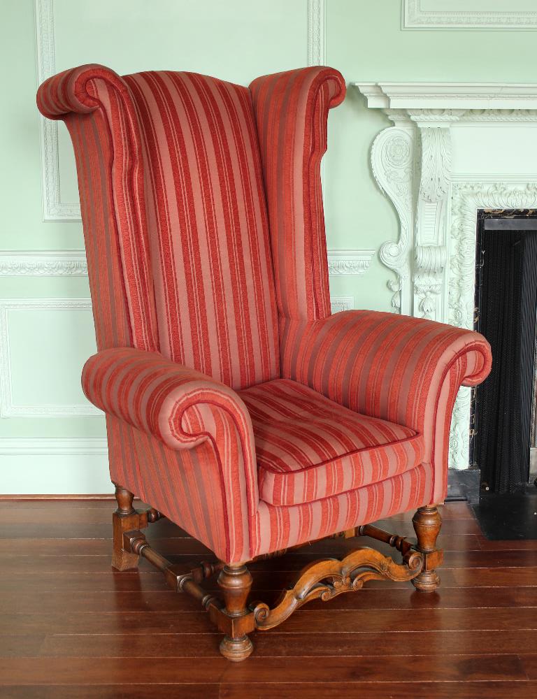 A large 17th century style upholstered armchair, with high back, out scrolling wings and arms on