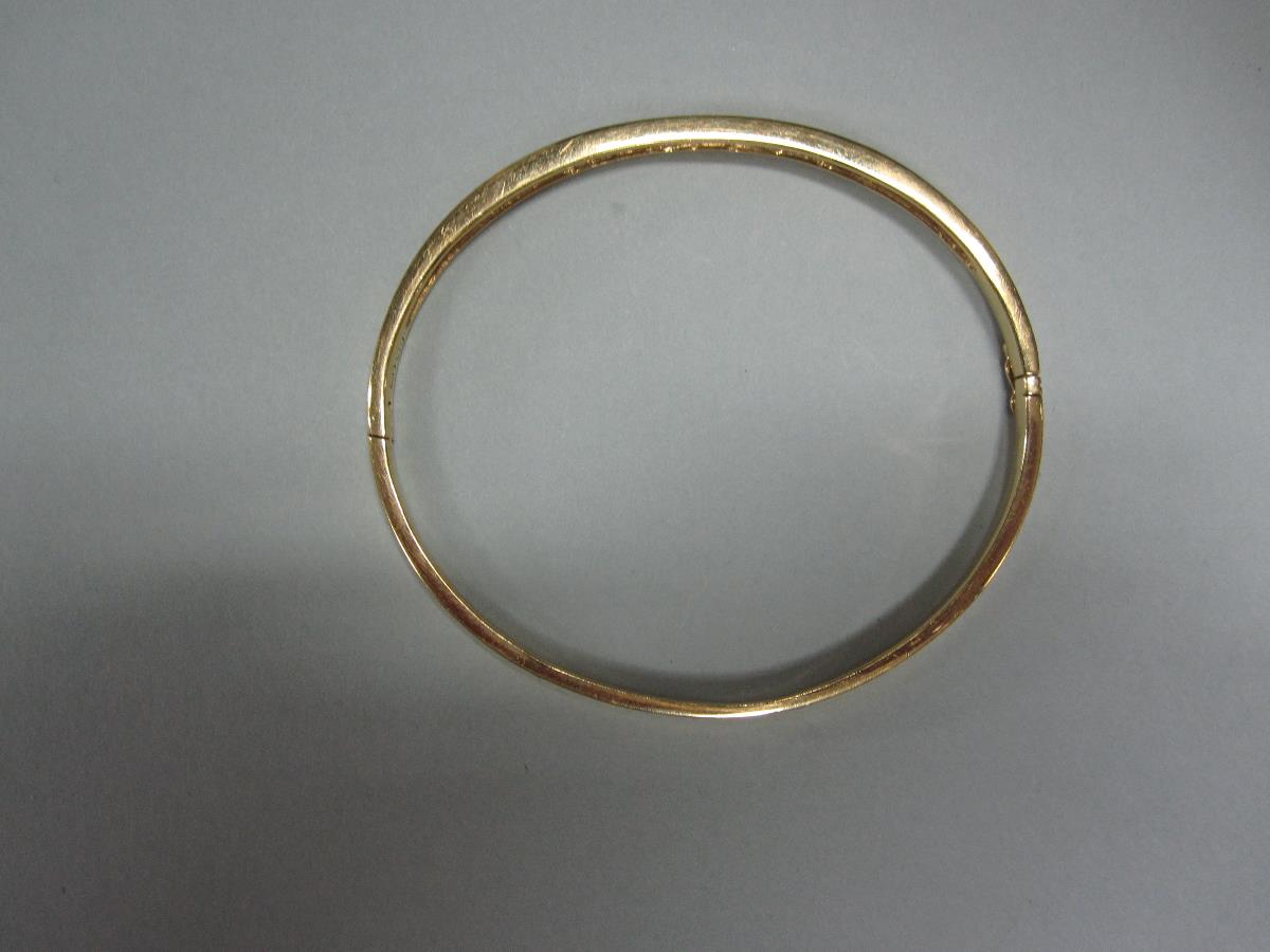 An 18ct gold and diamond hinged bangle, the plain narrow rectangular section bangle channel set to