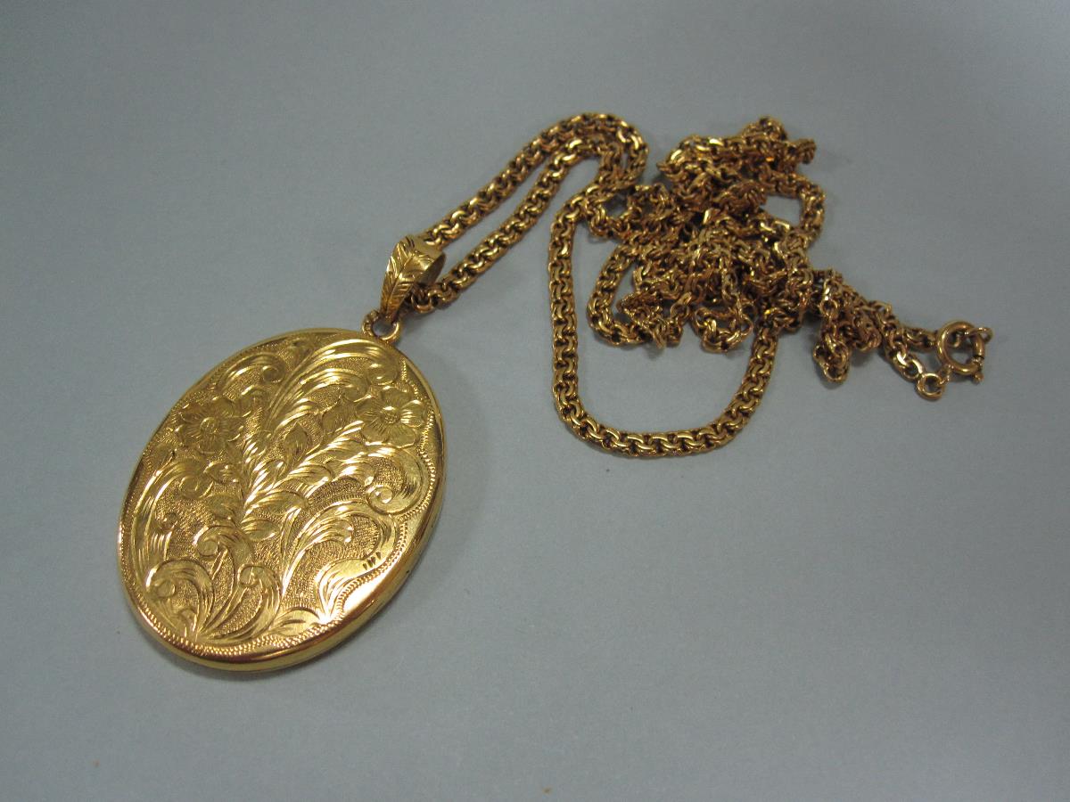 A 19ct gold locket and chain, the oval locket with bright cut decoration on one side and on the