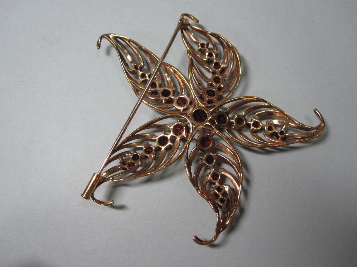 A mid 20th century garnet set flower brooch, of pierced asymmetric design with five veined boteh- - Image 3 of 3