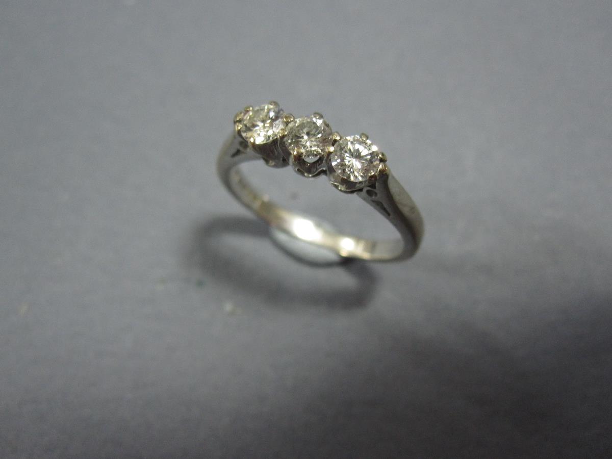 A three stone diamond ring set in 18ct white gold, the three uniform round brilliant cut diamonds