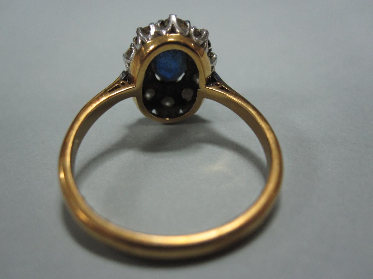 A sapphire and diamond cluster ring, the oval cut sapphire claw set in a border of ten round - Bild 3 aus 4