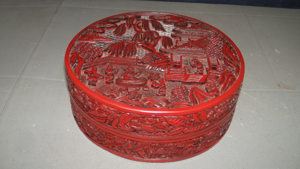 A cinnabar lacquer box and cover, the circular top carved in relief with a dignitary seated on a