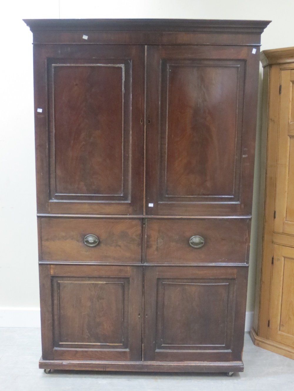 A mahogany wardrobe on castors. Height 200cm. Width 130cm. Depth 64cm.