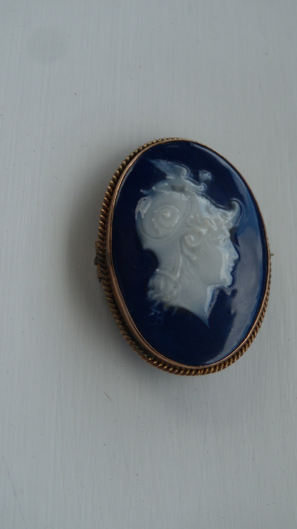 Attributed to Alboin Birks, a pate sur pate brooch, the oval shape painted in white slips with a